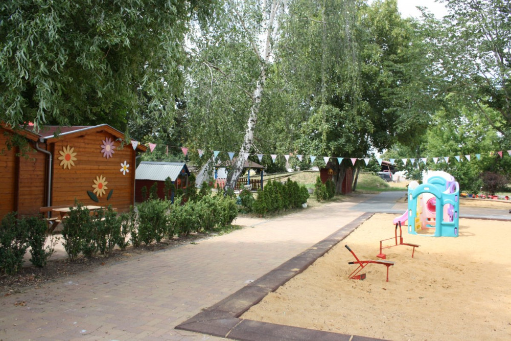 Außenansicht in Richtung Grünanlage mit kleiner Sandkiste im Vordergrund, Kinderland-Ringleben e.V.